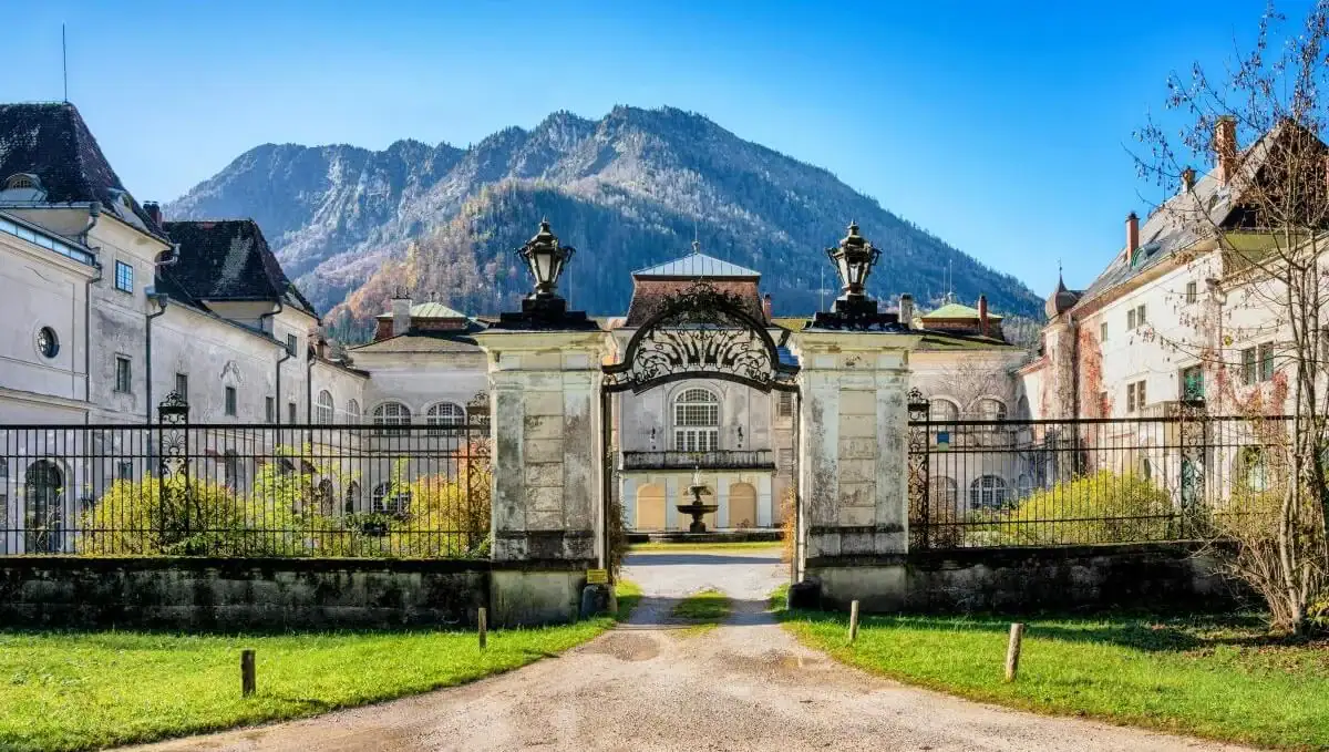 Elegant estate entrance with ornate gates and fountain, set against scenic mountain views in Switzer.