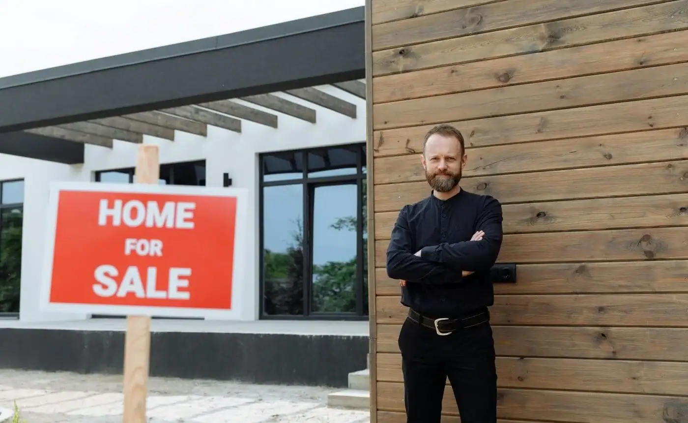 Home for sale sign outside a modern property with a real estate agent standing nearby.