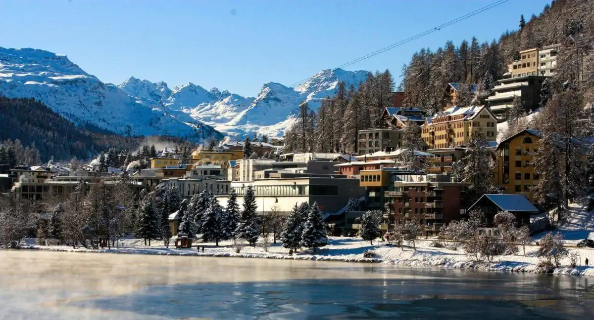 Mountain village with snow-covered buildings and surrounding peaks in winter.