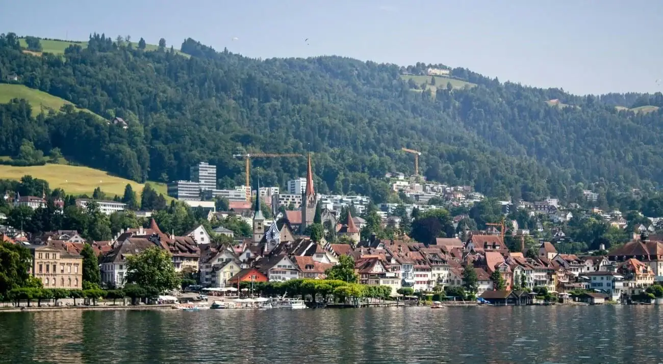 Beautiful lakeside town with colourful houses and lush green mountains in the background, ideal for.