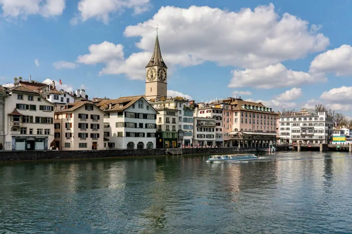 Scenic view of Swiss town with church tower and colorful buildings by the lake.