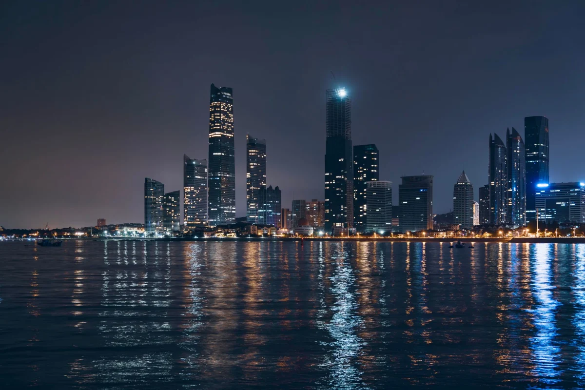 Vista notturna dello skyline di Abu Dhabi con riflessi sull'acqua, che mette in mostra l'architettura moderna.