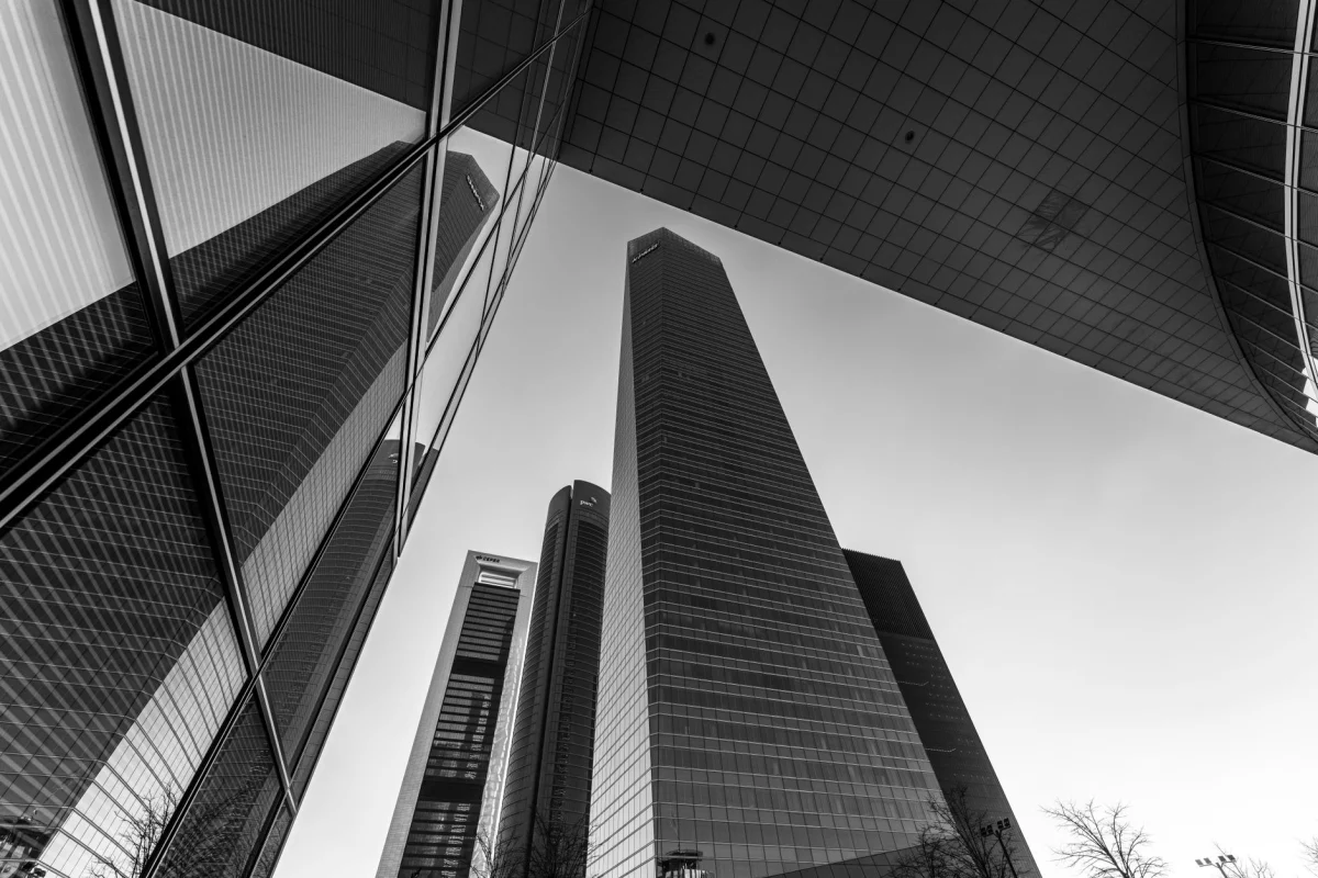 Low-angle black and white view of Madrid's iconic skyscrapers reflecting modern architecture.