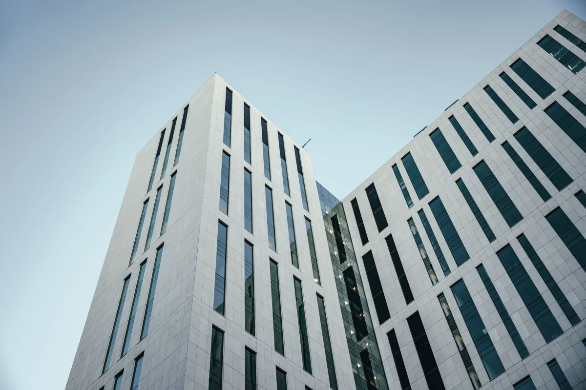 Dal basso di un edificio contemporaneo a più piani con design futuristico e finestre dalle forme insolite situate contro un cielo azzurro senza nuvole nelle strade della città