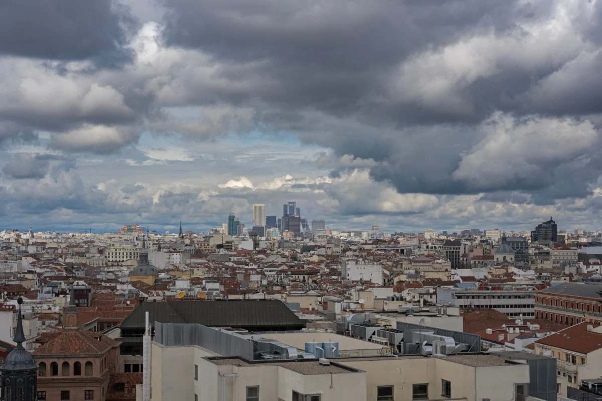 Aerial view of Madrid's skyline with dramatic clouds, featuring iconic skyscrapers and historic buildings.